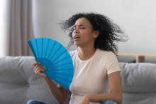 woman at home fanning herself, hot summer house