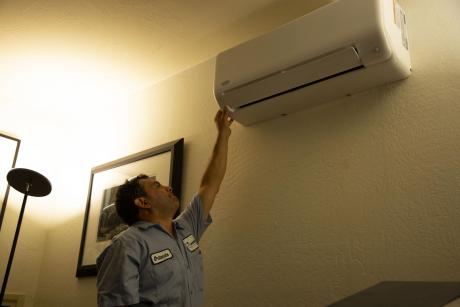 Hassler Employee inspecting wall mounted Heat Pump