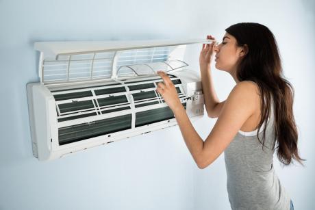 young woman inspecting air conditioner filter