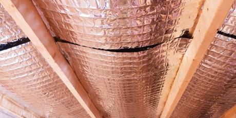 Insulating of attic with fiberglass cold barrier and reflective heat barrier