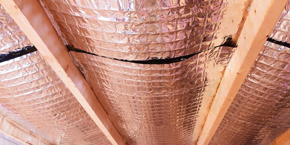 Insulating of attic with fiberglass cold barrier and reflective heat barrier