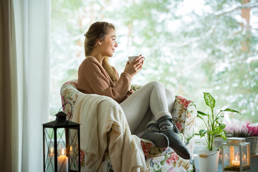 woman enjoying cup of tea in cozy room inside home